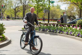 a man in a suit riding a bicycle