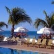 a pool with chairs and umbrellas by the ocean