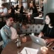 a man and woman sitting at a table with a laptop