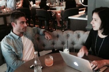 a man and woman sitting at a table with a laptop