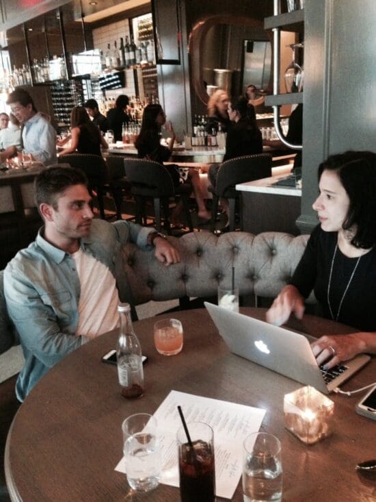 a man and woman sitting at a table with a laptop