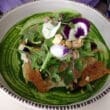 a salad with flowers and nuts in a bowl