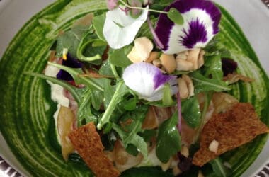 a salad with flowers and nuts in a bowl