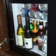 a glass cabinet with bottles and cans