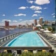 a pool with chairs and umbrellas next to a body of water