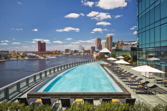 a pool with chairs and umbrellas next to a body of water