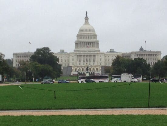 a large white building with a dome and a green lawn