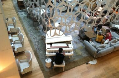 a man playing piano in a room with chairs and a sofa