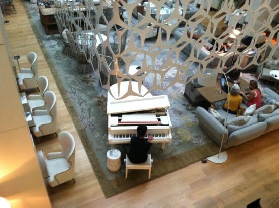 a man playing piano in a room with chairs and a sofa