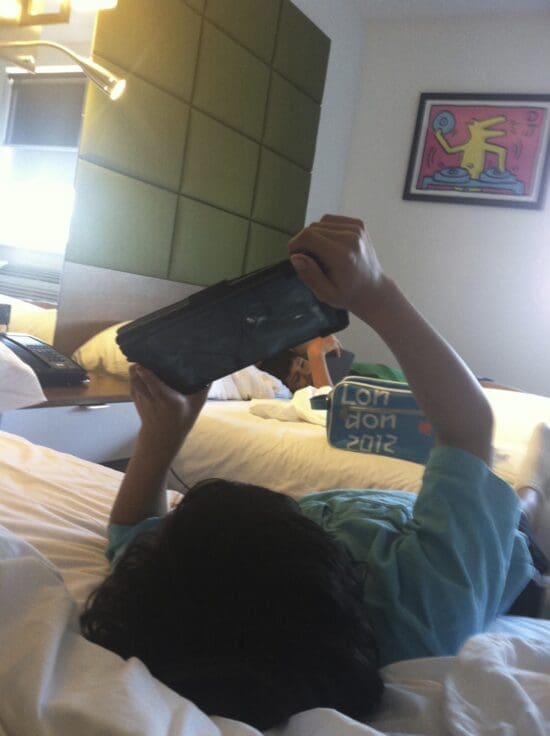 a person lying on a bed holding a device