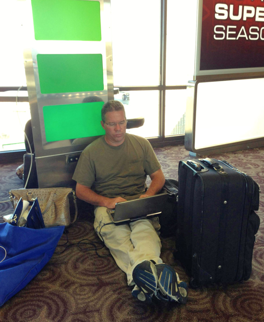 PHOENIX - Road warrior Kelley Hammel of Denver huddles near a power outlet. Photo by Barb DeLollis.