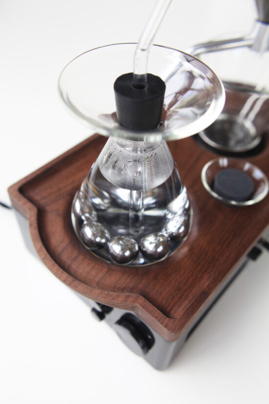 a glass container with a metal object on top