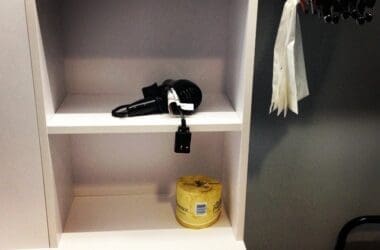 a shelf with a hair dryer and a roll of tape