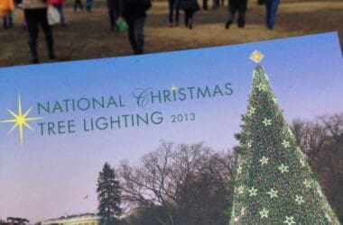 a person holding a postcard with a christmas tree and people in the background