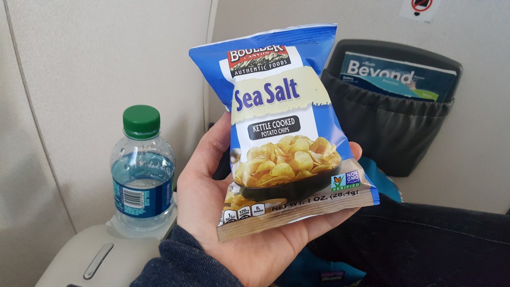 A bag of chips being held up during the in-flight meal service aboard an Alaska Airlines flight in first class