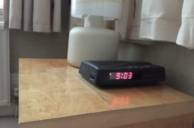 a black alarm clock on a table next to a lamp