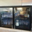 a refrigerator with bottles of water and cans of soda