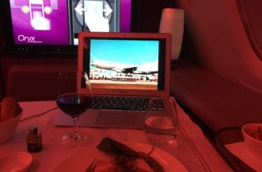 a laptop on a table with a plate of food and a plate of wine