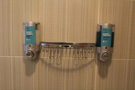 a soap dispenser and a rack on a wall