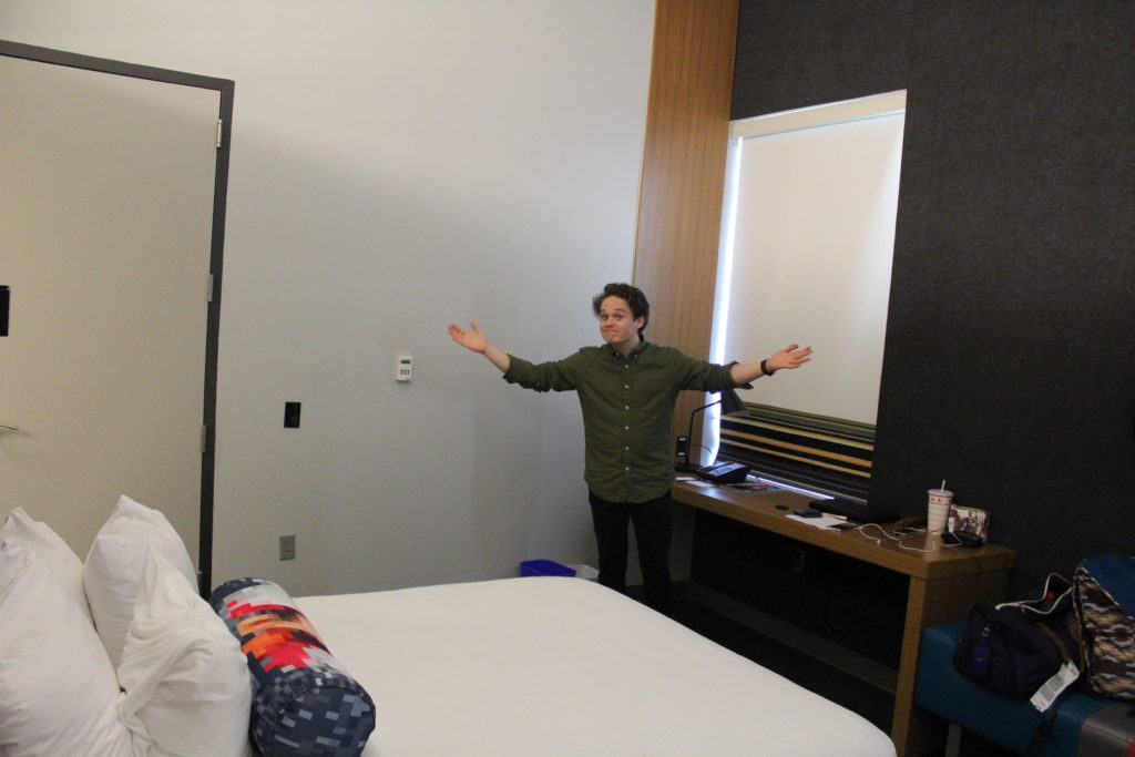 A person standing in a hotel room with their hands up.