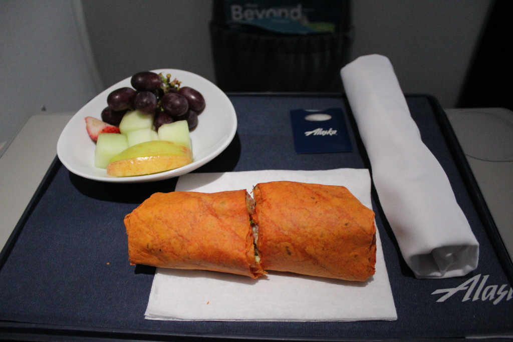 A breakfast burrito served alongside assorted fruit during the in-flight meal service on an Alaska Airlines E175 in first class.