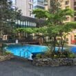 a swimming pool with trees and plants in front of buildings