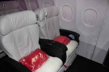 a pair of white seats with red pillows in a plastic bag