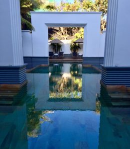a pool with a white wall and columns