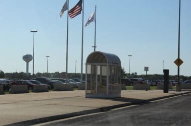 a glass bus stop with flags on poles