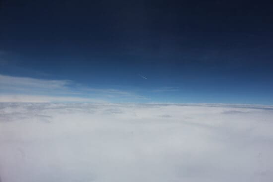 a blue sky with clouds and a plane flying in the sky