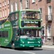 a green double decker bus on the street