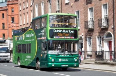 a green double decker bus on the street