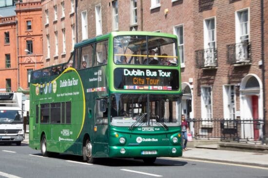 a green double decker bus on the street