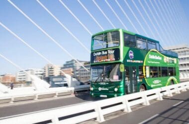 a green double decker bus on a bridge