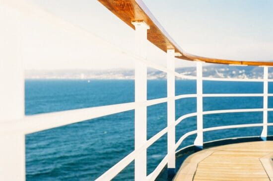 a deck with white railings and a body of water