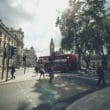 a red double decker bus on a street with people walking around