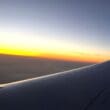 an airplane wing with the sun setting in the background