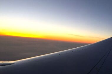 an airplane wing with the sun setting in the background