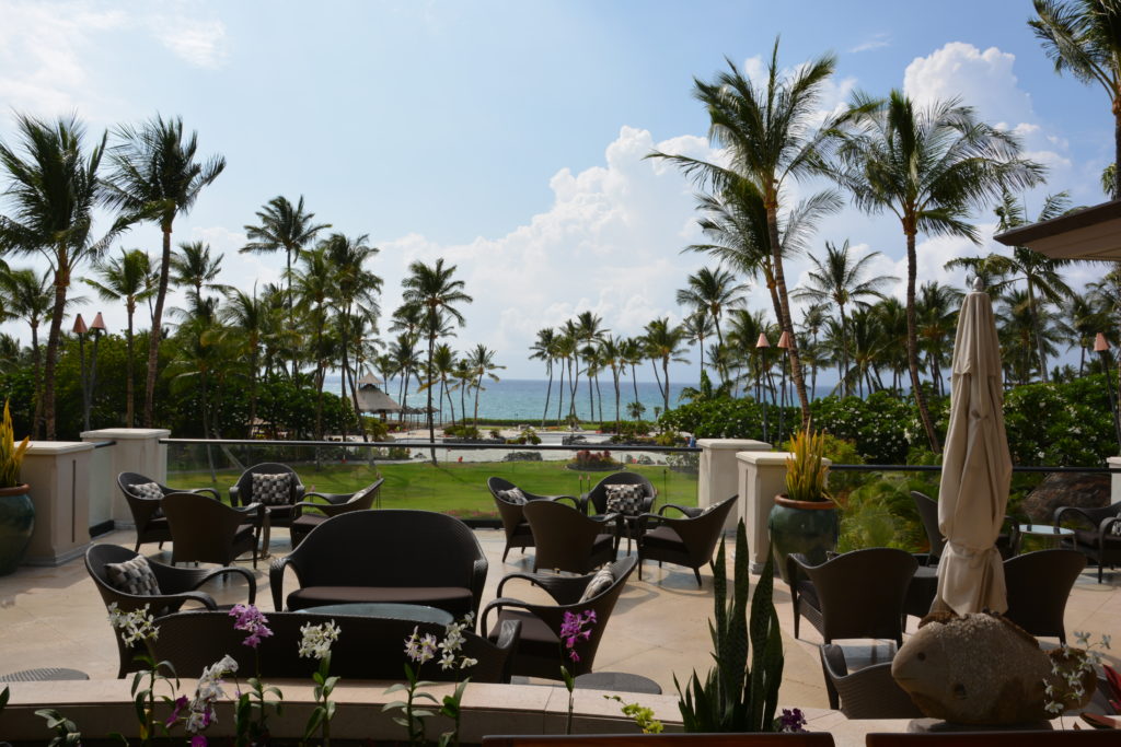 a patio with chairs and trees and a body of water