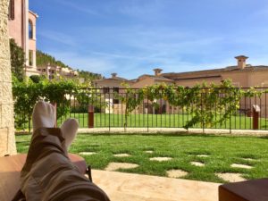 a person's legs on a chair in a yard