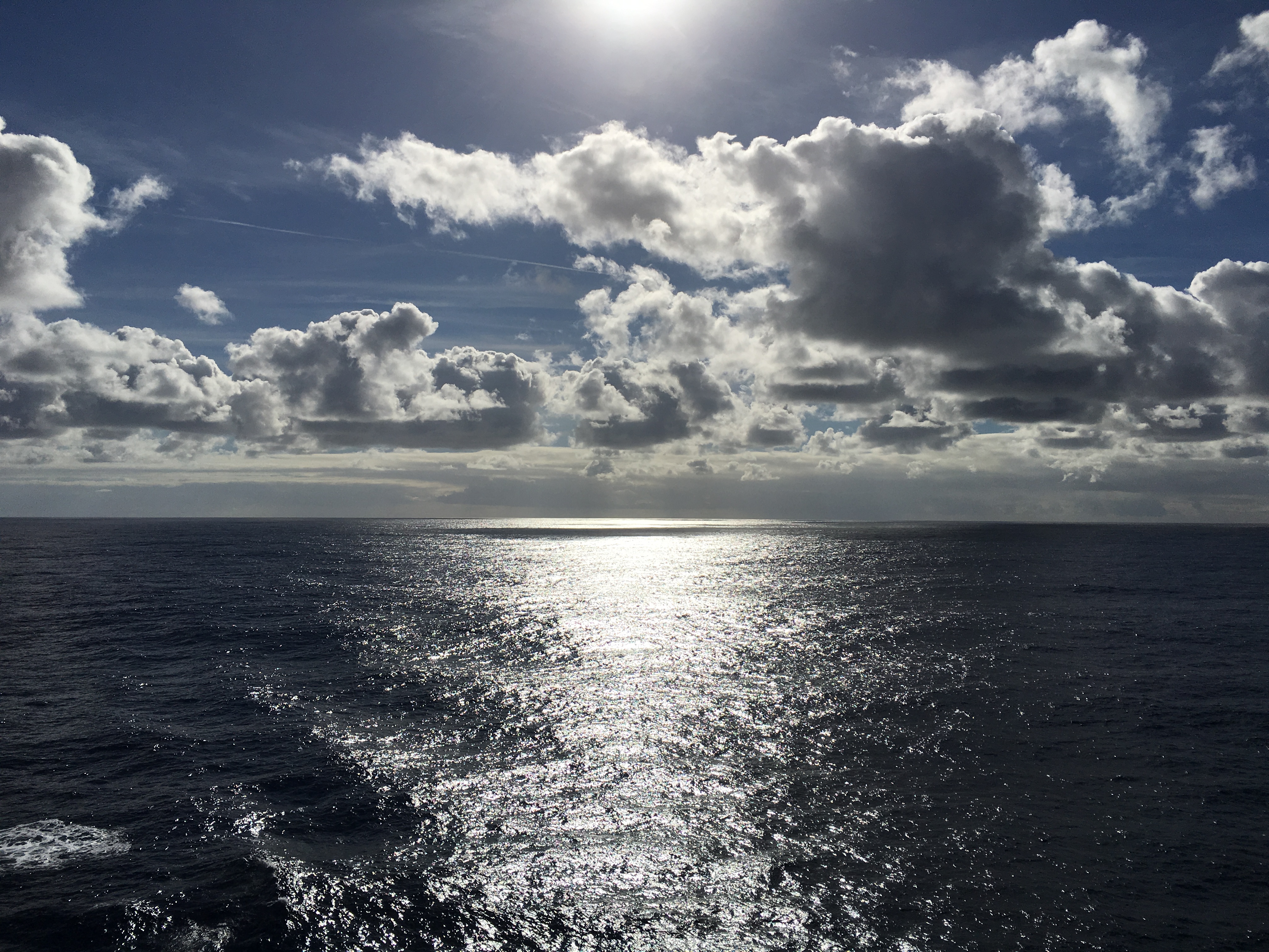 a body of water with clouds and sun