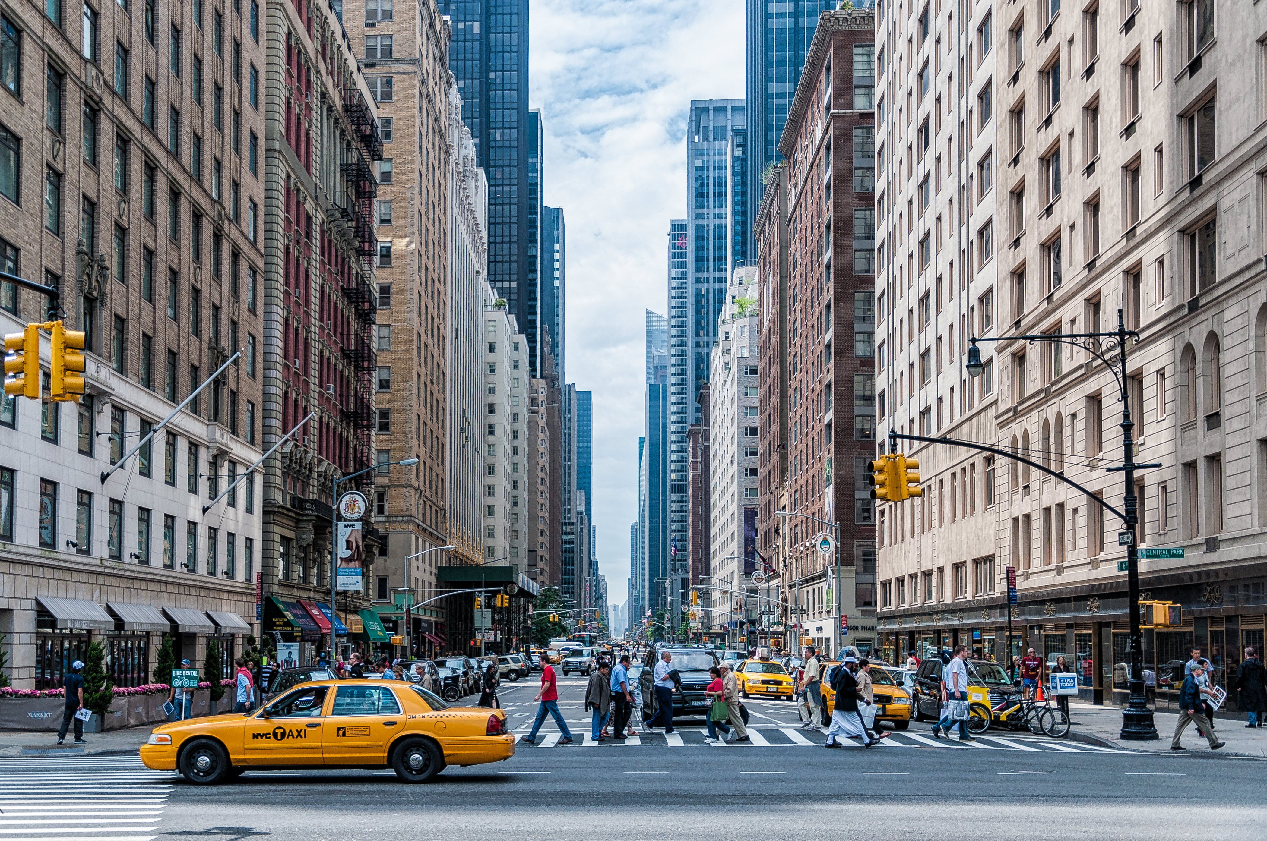 a city street with many tall buildings and people crossing it