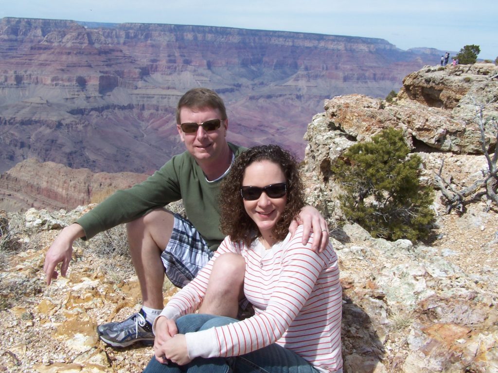 a man and woman sitting on a rock