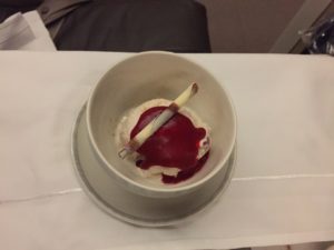 a bowl of ice cream with a red liquid and a brush