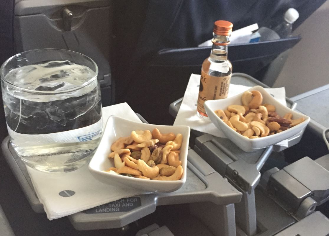 a bowl of nuts and a glass of water on a tray