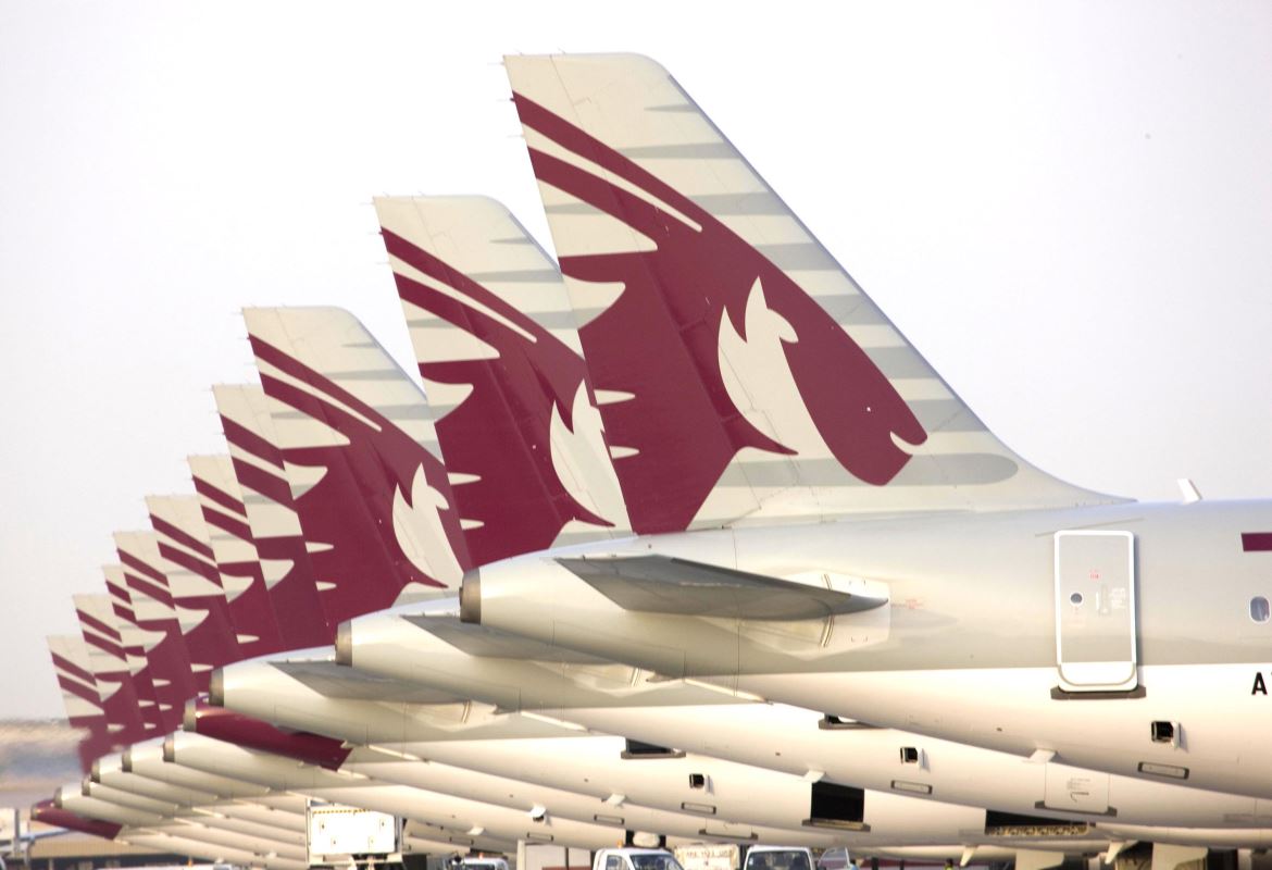 a row of airplanes with red tail fin