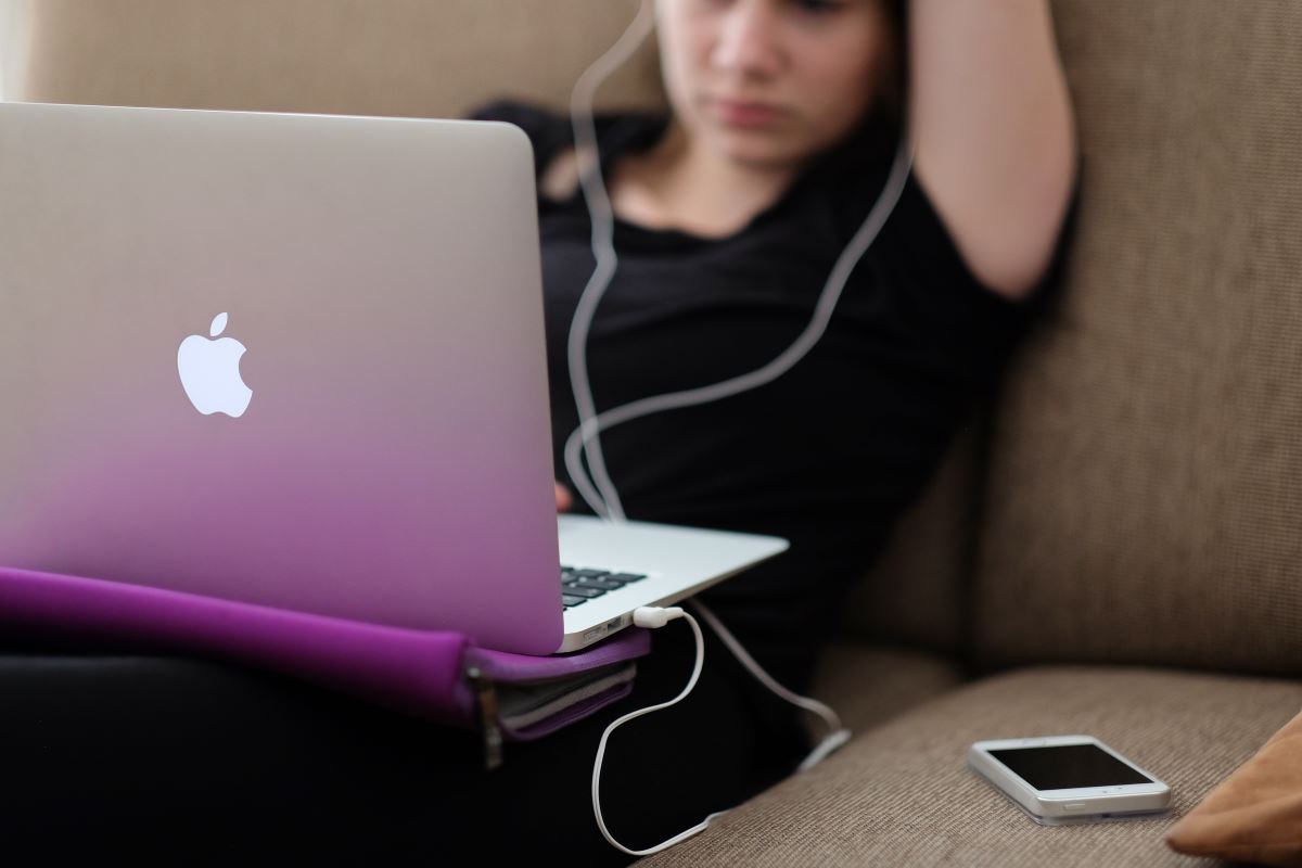 a woman sitting on a couch with a laptop and a cell phone