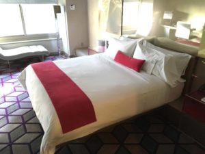 a bed with white sheets and red pillows