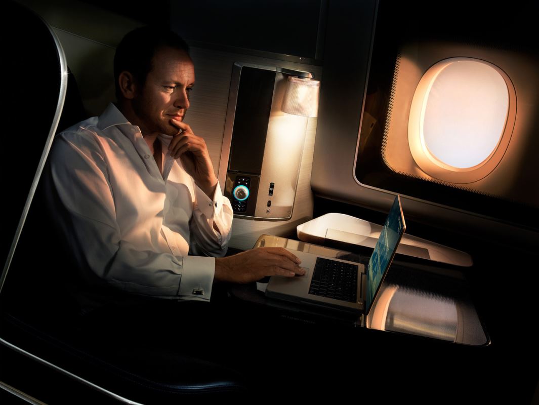 a man sitting in an airplane using a laptop