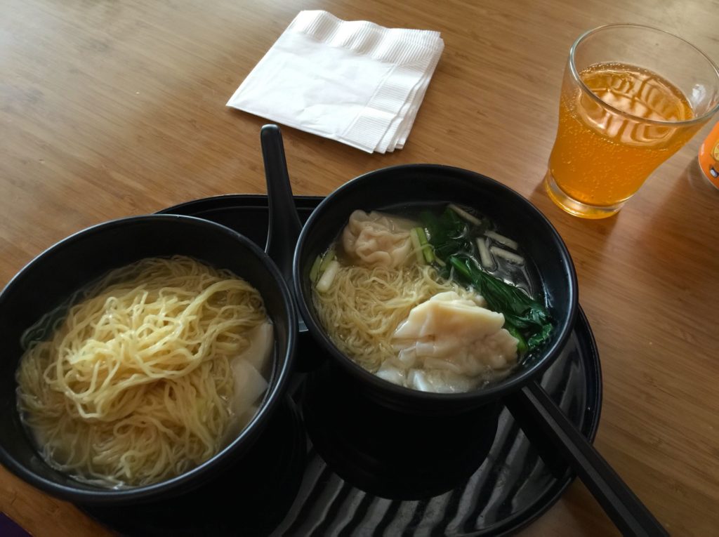 a bowl of soup with noodles and a glass of liquid